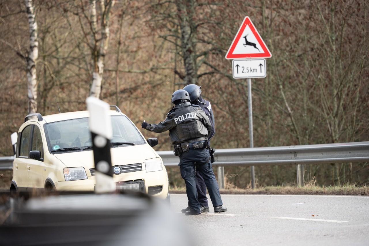 31.01.2022, Rheinland-Pfalz, Mayweilerhof: Polizeibeamte kontrollieren an einer Absperrung an der Kreisstraße 22, rund einen Kilometer von dem Tatort entfernt, an dem zwei Polizeibeamte durch Schüsse getötet wurden, ein Auto.