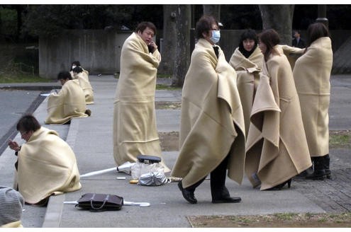In Yokohama wickeln sich gestrandete Pendler in Decken. Sie wollen in einem Park übernachten.