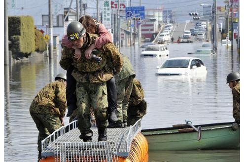 In seiner Heimat gehen die Rettungsarbeiten unermüdlich weiter. Hier wird eine Frau in Ishimaki von Helfern aus der Gefahrenzone gebracht.