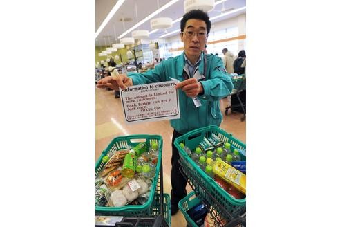 Das Schild, das der Mitarbeiter des Supermarktes aushängt, besagt: Kunden können nur noch kleine Mengen an Waren kaufen.