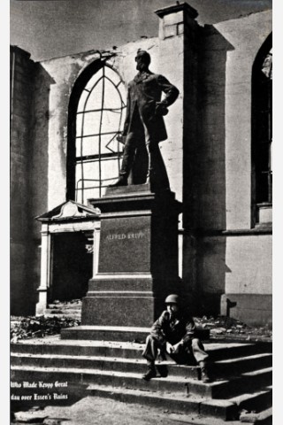 Ein Soldat der Alliierten sitzt 1945 auf den Stufen der zerstörten Marktkirche vor dem Denkmal von Alfred Krupp.