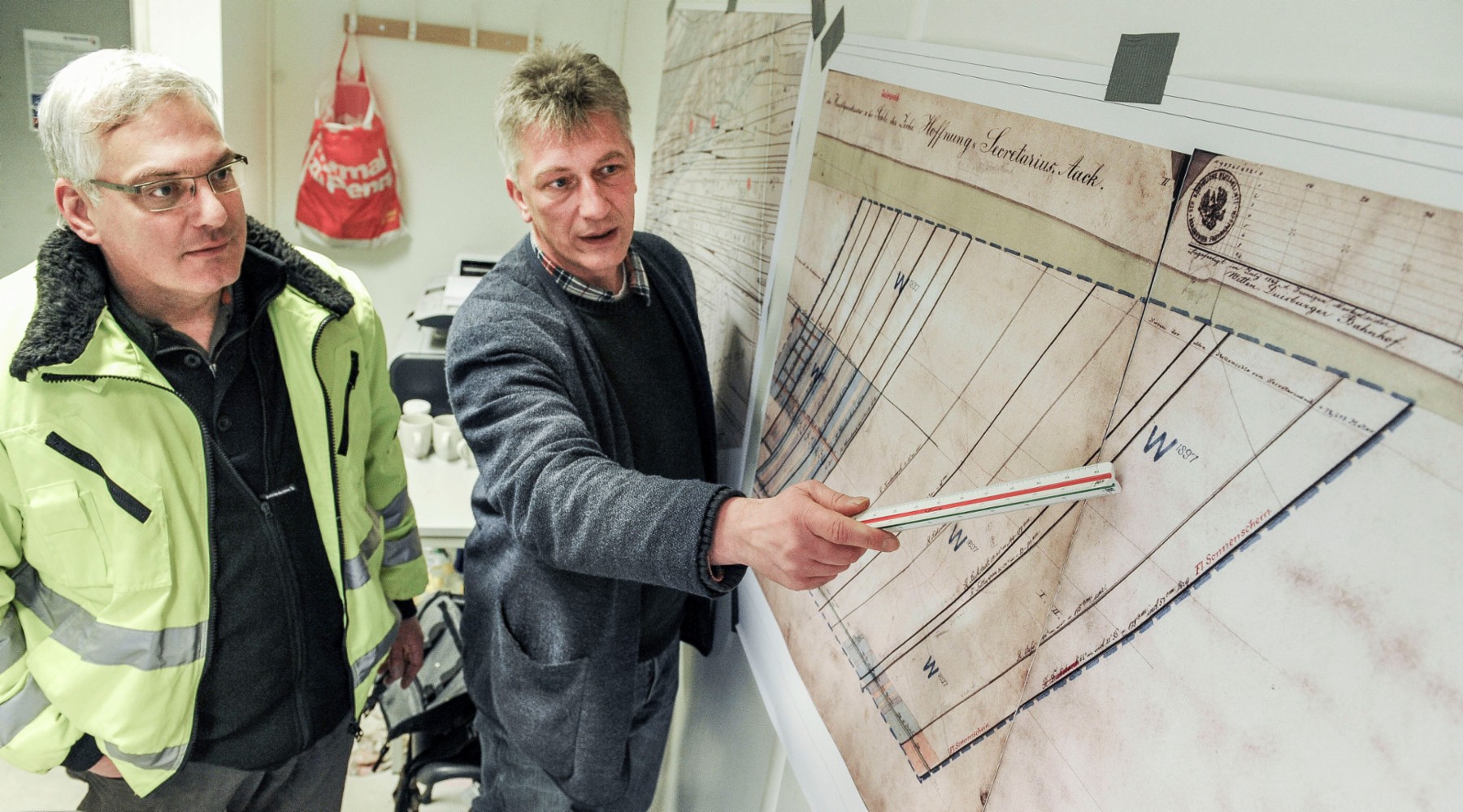 Jürgen Schauwecker (GF GBE Grundbau) und Frank Jurga (DMT Projektmanager) an einer alten Karte, auf der Stollen und Flöze aus dem 19. Jahrhundert verzeichnet sind. Foto: Knut Vahlensieck / WAZ Fotopool  