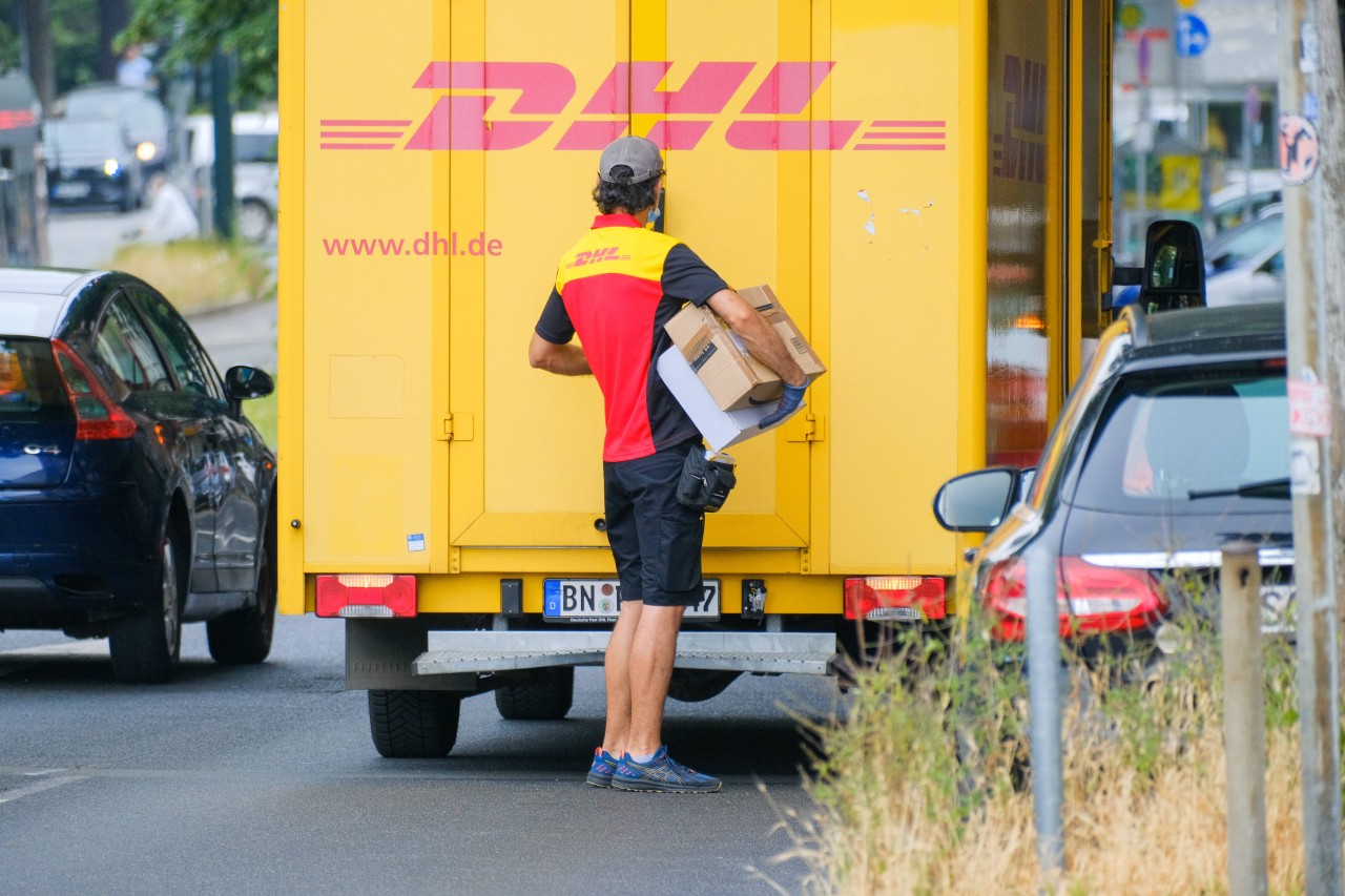 Eine Bote von der DHL verteilt Pakete.