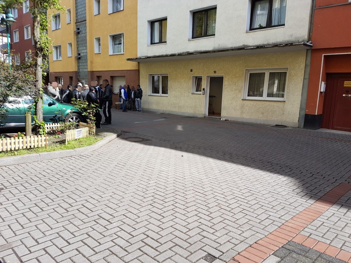 Misstrauische Blicke und eisernes Schweigen: Vor dem Haus des erstochenen Jungen (14) an der Henriettenstraße sammeln sich am Dienstagmorgen Dutzende Männer.,