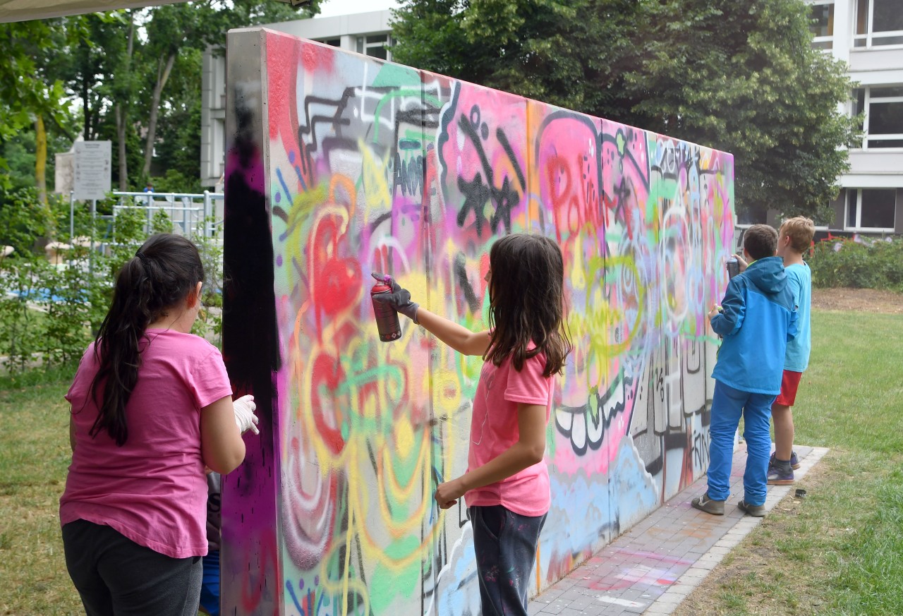 Kinder sprühen an der legalen Graffitiwand bei der Einweihung einer Parkours-Anlage am Kußweg.