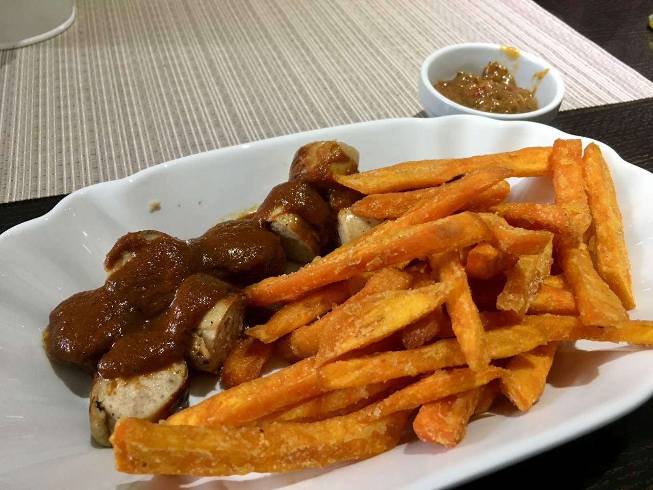 Currywurst mit Süßkartoffelpommes und Erdnusssauce bei „Frank's Fleischermeister Grill“ in Essen-Frohnhausen.