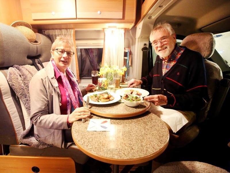 Dorothea und Hubert sitzen in ihrem Wohnmobil am Esstisch.