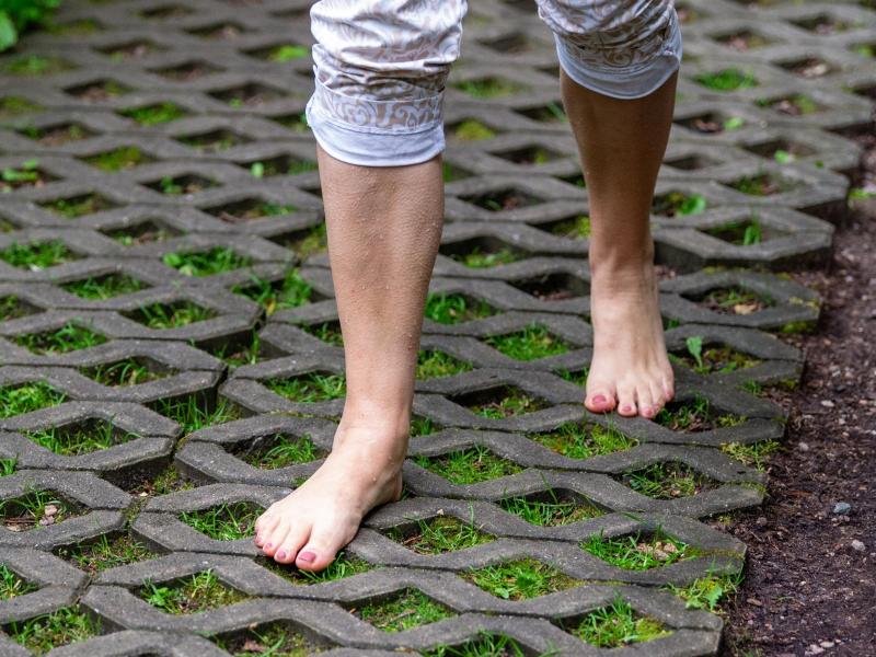 Eine Frau geht im Barfußpark über verschiedene Untergründe. 60 verschiedene Stationen gibt es insgesamt.