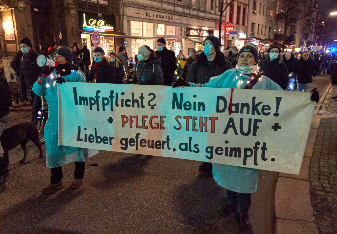 Teilnehmer einer Demonstration gegen die Corona-Maßnahmen in Hamburg halten ein Transparent mit der Aufschrift „Impfpflicht? Nein Danke! Pflege steht auf. Lieber gefeuert, als geimpft“.