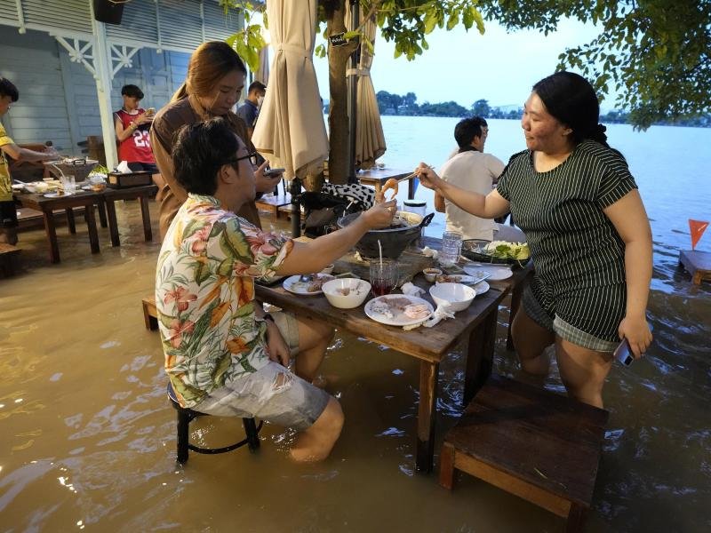 Menschen sitzen trotz des hohen Wasserstands im "Chaopraya Antique Café". Das von der Flutkatastrophe betroffene Restaurant hat sich zu einem Hotspot entwickelt.