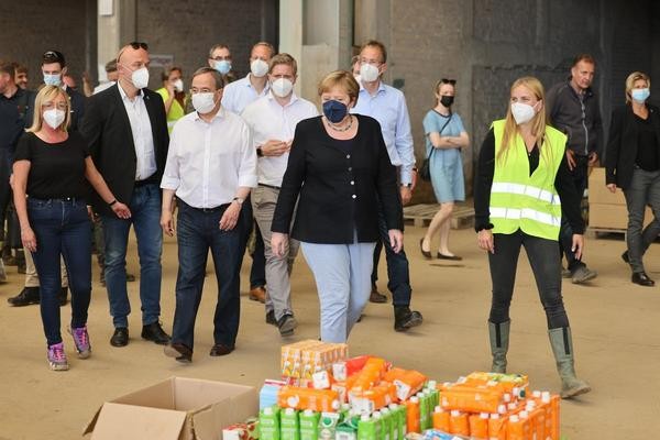 Bundeskanzlerin Angela Merkel (CDU, M)und der Ministerpräsident von Nordrhein-Westfalen Armin Laschet (CDU, 3.v.l) besichtigen ein Lager mit Lebensmitteln bei ihrem Besuch im vom Hochwasser betroffenen Gebiet von Bad Münstereifel. 