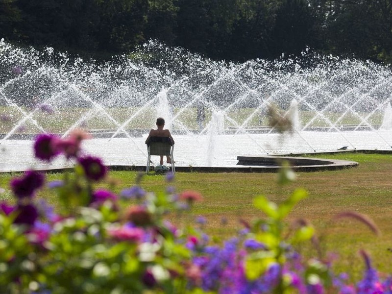 Ein Mann sitzt zur Abkühlung an den Wasserfontänen im Nordpark. Foto: Bernd Lauter / WAZ FotoPool