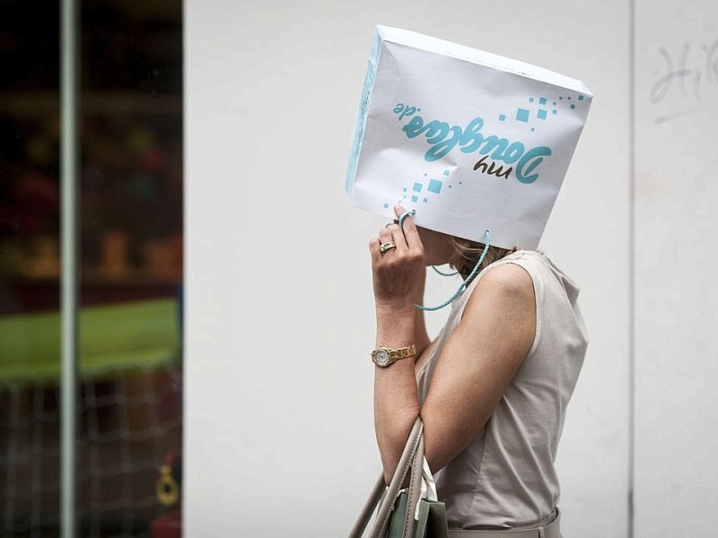 Eine Frau schützt sich mit einer Einkaufstüte vor dem Regen in der Altstadt in Düsseldorf.Foto: Bernd Lauter / WAZ FotoPool