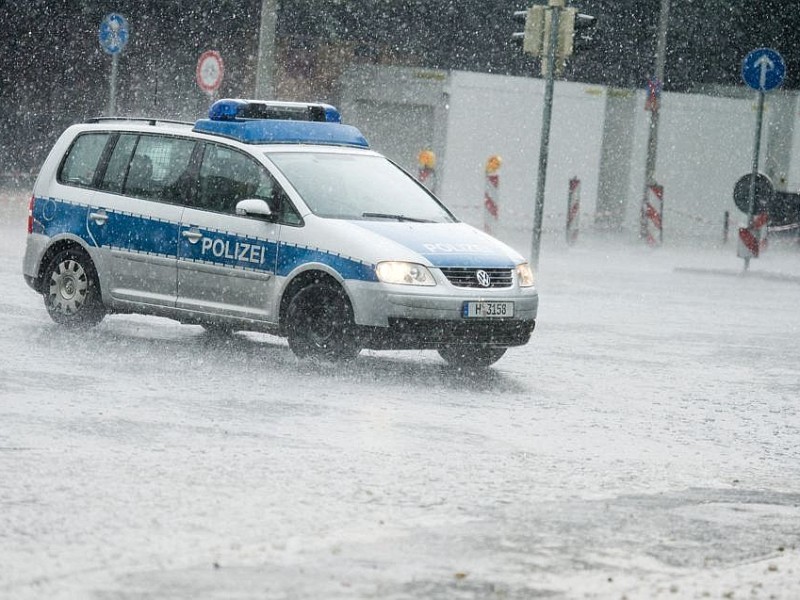 Ein Polizeifahrzeug fährt während eines Unwetters über eine Straße in Hannover.