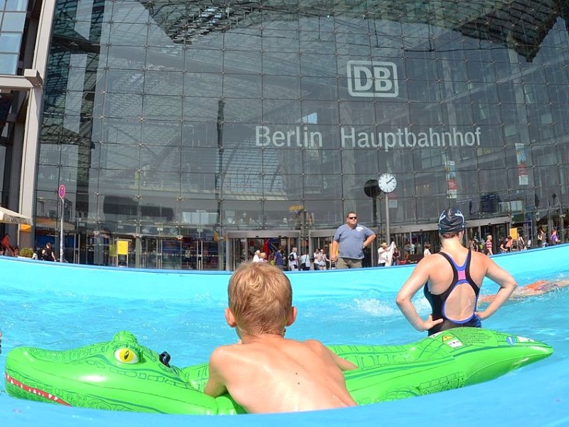 Kinder und Erwachsene kühlen sich am Hauptbahnhof in Berlin bei Temperaturen um 35 Grad in einem Wasserbecken ab.