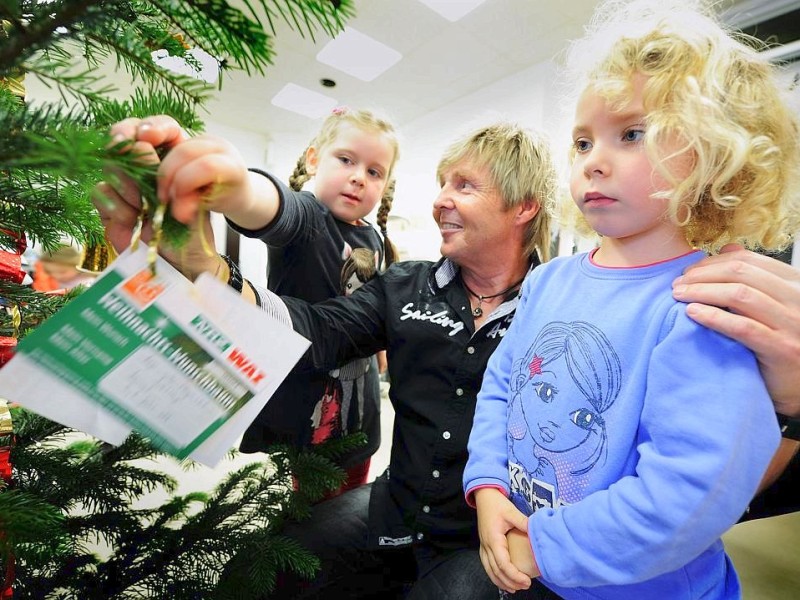 Am 18.11.2011 findet in Moers die Weihnachtswunschbaumaktion der NRZ/WAZ in Zusammenarbeit mit dem Verein Klartext für Kinder e.V. statt. Kiunder der Kindergärten aus der Region hängen Wunschzettel an Weihnachtsbäume in den Räumlichkeiten von Geldinstituten und des Einzelhandels. Im Bild: Emma (li.), Lilly (re.) und Coiffeur Wolfgang DedtersFoto: Matthias Graben / WAZ FotoPool