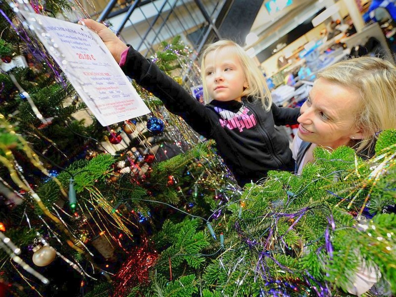 Am 18.11.2011 findet in Moers die Weihnachtswunschbaumaktion der NRZ/WAZ in Zusammenarbeit mit dem Verein Klartext für Kinder e.V. statt. Kiunder der Kindergärten aus der Region hängen Wunschzettel an Weihnachtsbäume in den Räumlichkeiten von Geldinstituten und des Einzelhandels. Im Bild: Bärbel Filip (Koordinatorin des Jugendamtes Kamp-Lintfort) und Dorien hängen einen Wunschzettel an den Wunschbaum.Foto: Matthias Graben / WAZ FotoPool