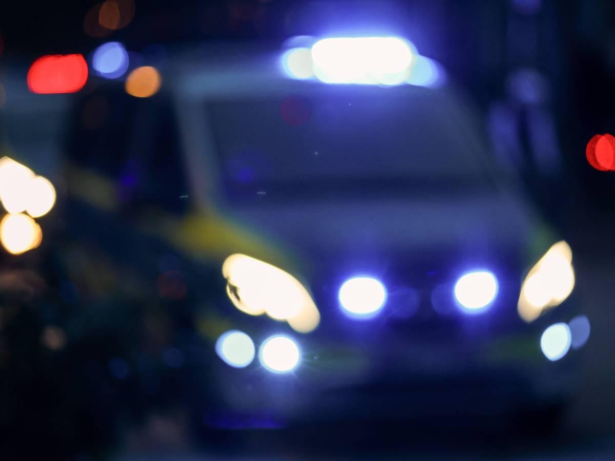 Ein Fahrzeug der Polizei steht mit eingeschaltetem Blaulicht auf einer Straße.