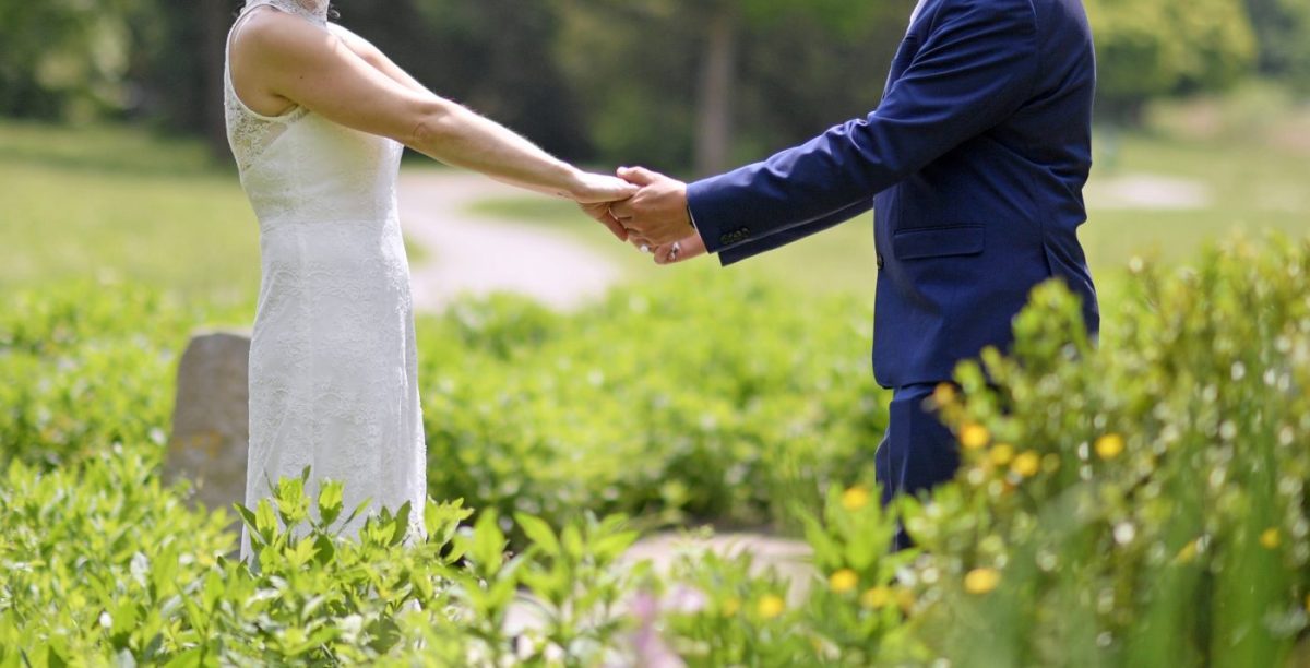Hochzeit Brautpaar Hand in Hand auf Wiese
