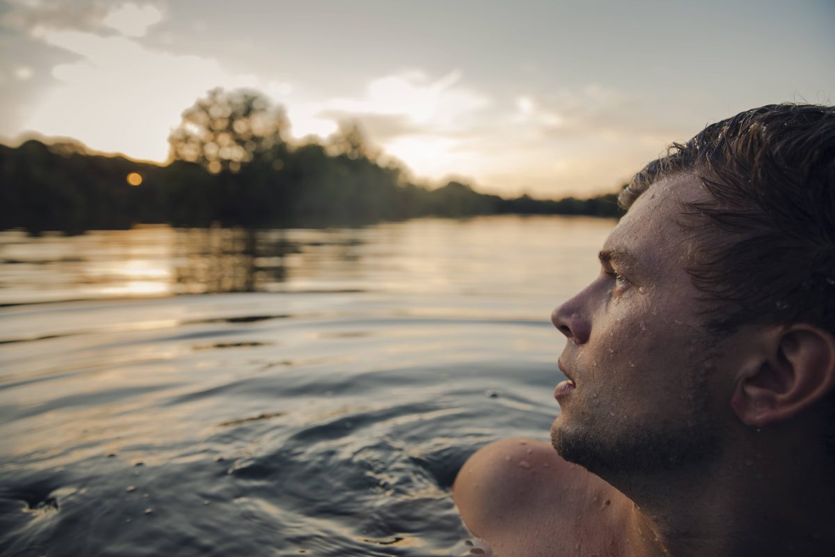 Junger Mann schwimmt im Wasser und schaut in den Himmel