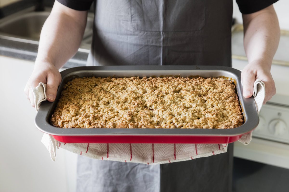 Bäcker hält ein Backblech Streuselkuchen