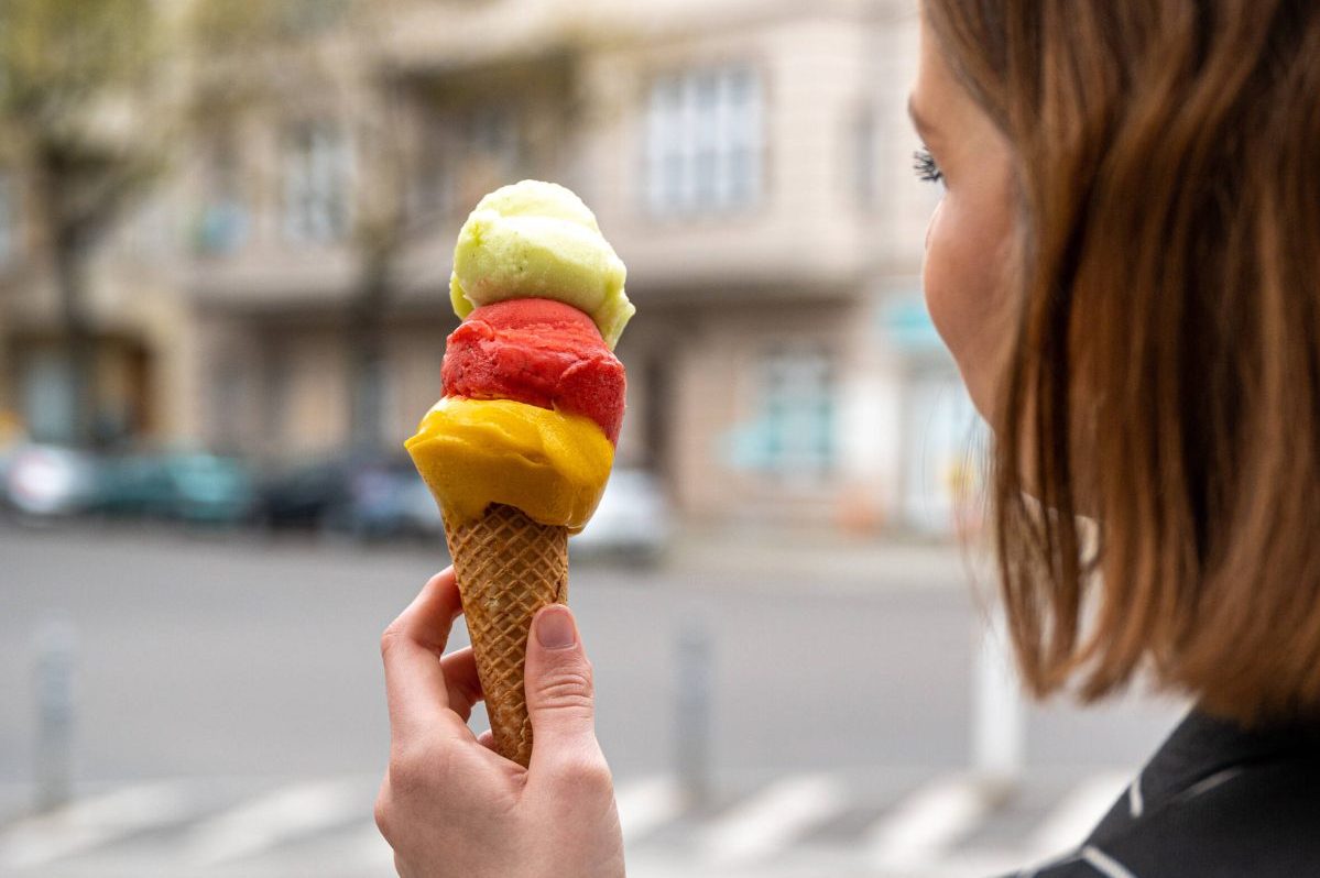 Frau hält Eistüte mit drei Fruchtkugeln in der Hand