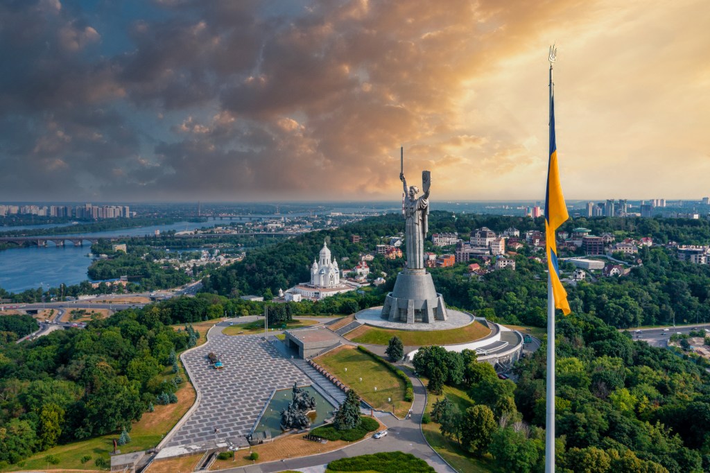 Ukrainische Flagge im Wind vor der Statue des Landes.