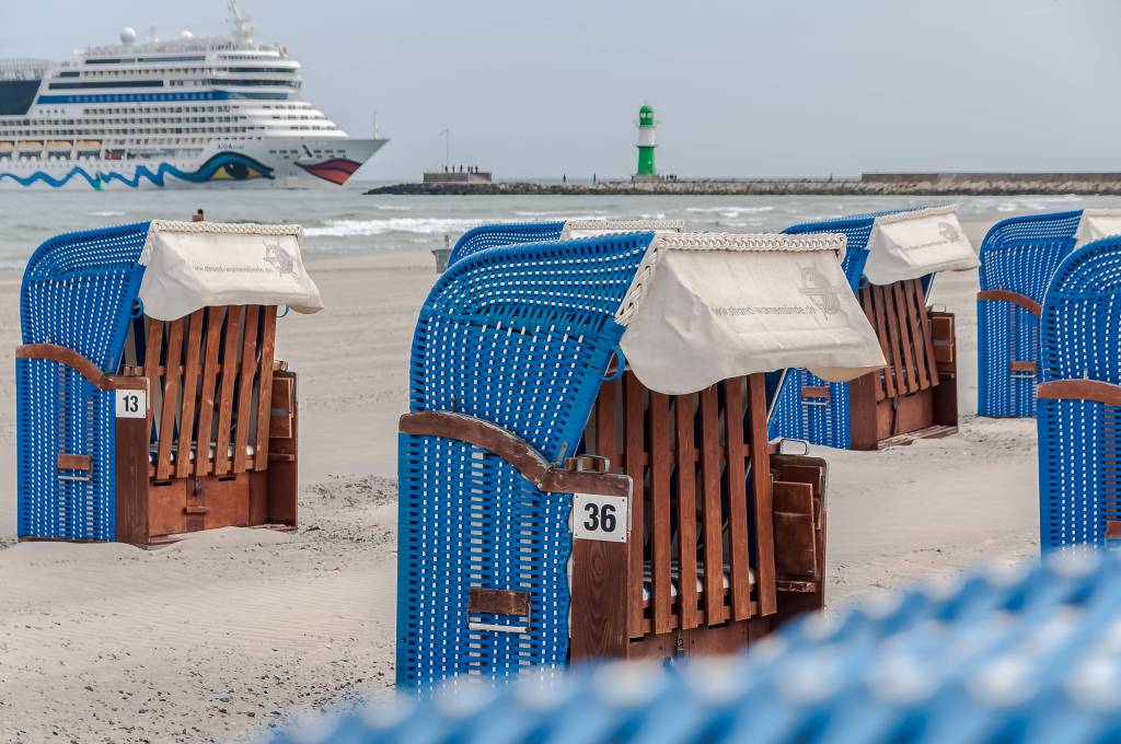 Geschlossene Strandkörbe mit Aida Schiff im Hintergrund.