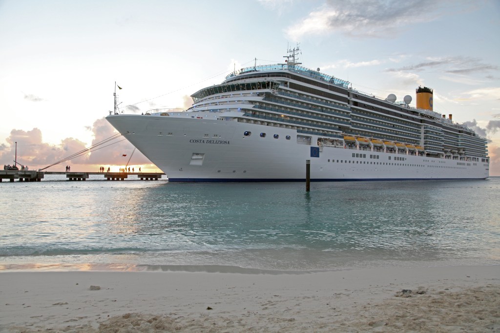 Ein Kreuzfahrtschiff am weißen Sandstrand.