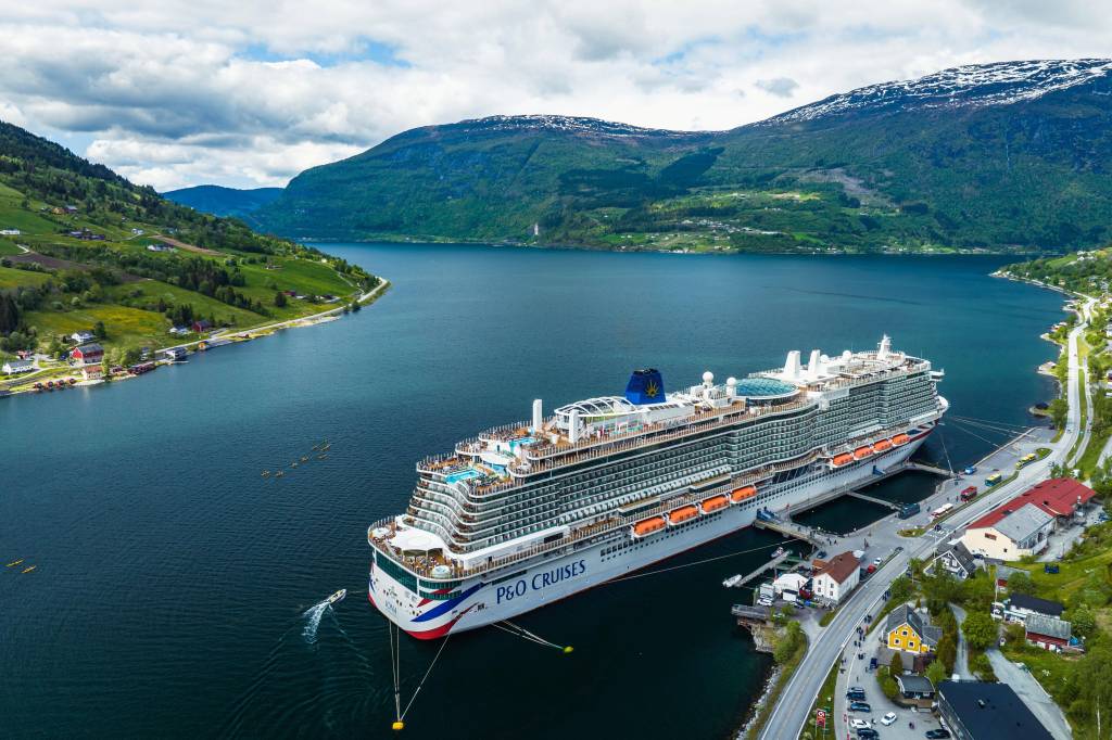 Großes Kreuzfahrtschiff in skandinavischer Landschaft.