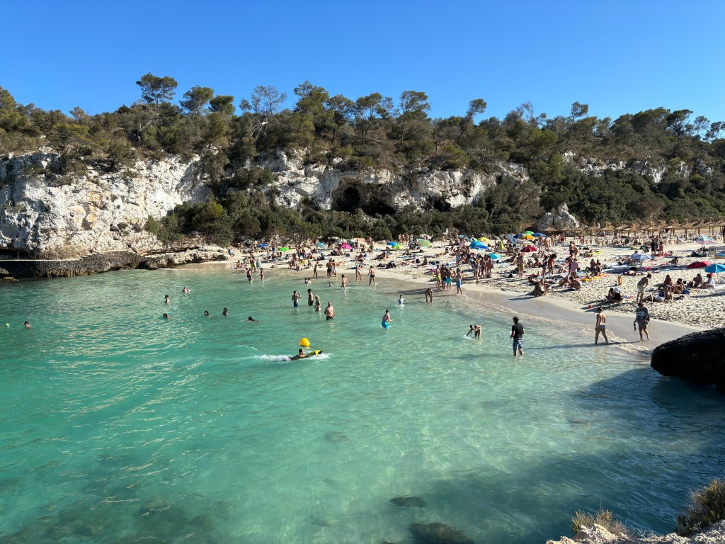 Kleiner Strandabschnitt mit badenden Menschen.