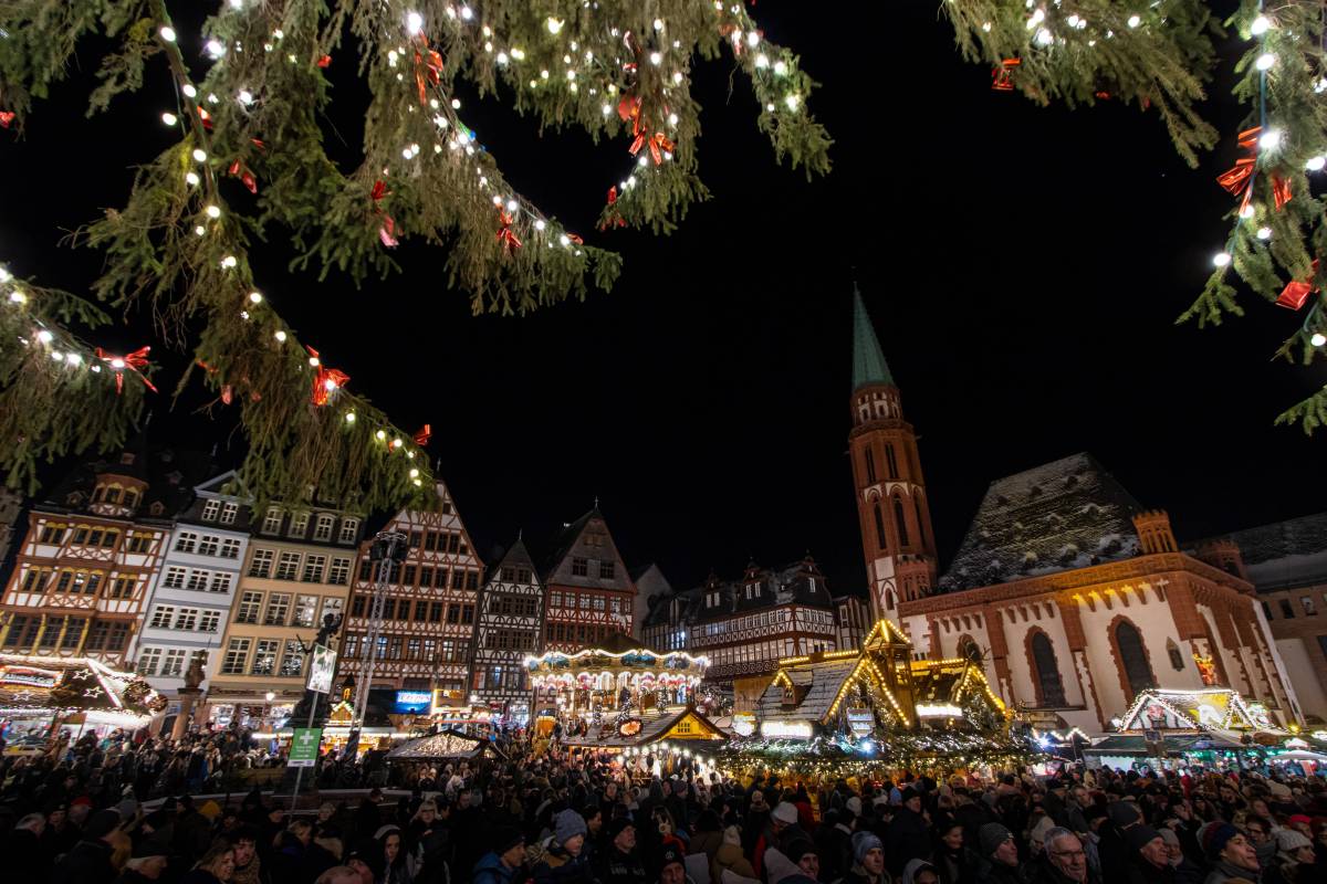 Ausblick auf großen Weihnachtsmarkt hinter Tannenzweigen.